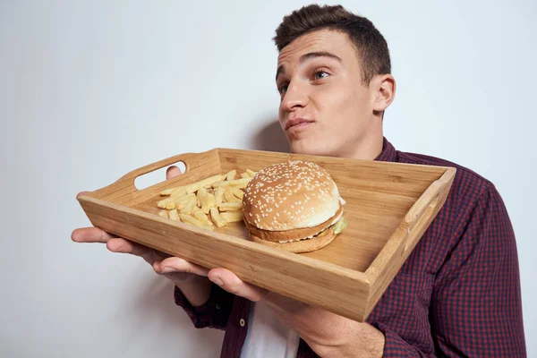 Ein Mann hält in Nahaufnahme einen Pommes-Hamburger in einem Fast-Food-Restaurant — Stockfoto