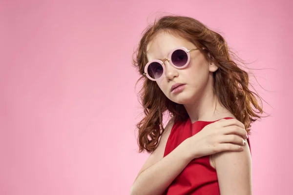 Fille avec des lunettes de soleil cheveux bouclés joie de l'enfance fond rose — Photo