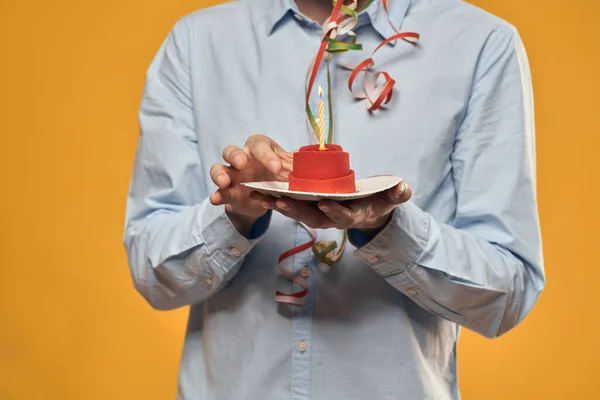 Un hombre sosteniendo un pastel en un plato y una vela desde arriba fondo aislado — Foto de Stock