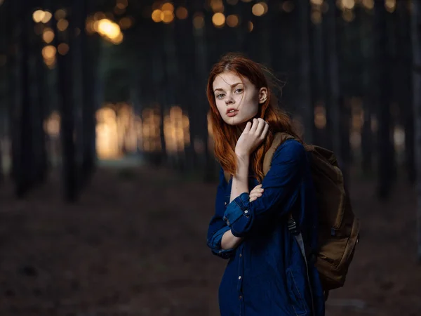 Hezká žena cestuje v lese s batohem na zádech a v modré košili — Stock fotografie