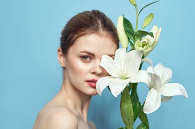 Mavi arka planda beyaz çiçekli bir kadın çıplak omuzları kesiyordu.