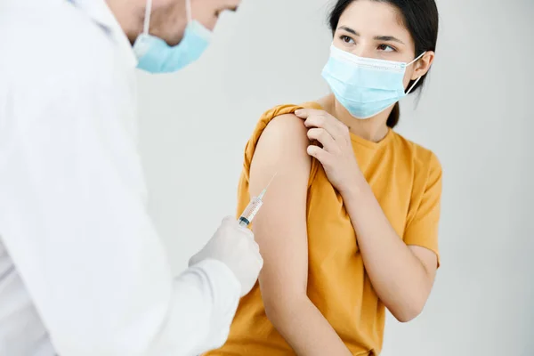 Läkare i medicinsk mask injicera en kvinna skuldra vaccination injektion hälsoskydd mot virus covid — Stockfoto