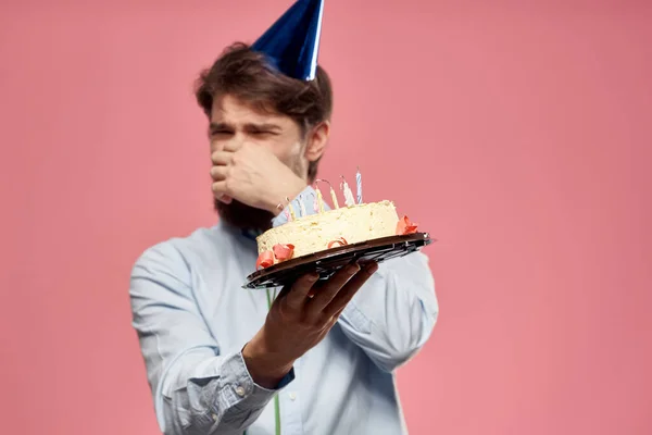 Hombre con pastel en un plato y en una camisa azul sobre un fondo rosa cumpleaños vacaciones vista recortada — Foto de Stock