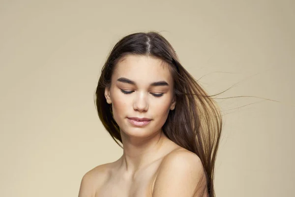 Mulher bonita ombros nus cabelos longos cuidados com o corpo fundo bege — Fotografia de Stock