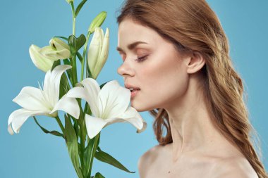 Mavi arka planda beyaz çiçekli bir kız. Kızıl saç portresi modeli.