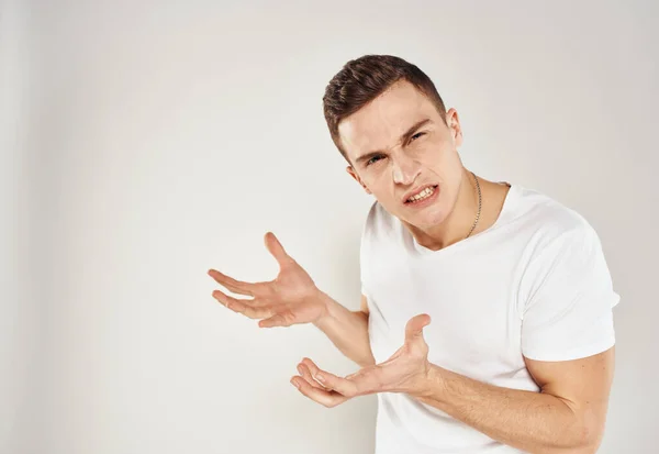 Un gars dans un T-shirt blanc émotions irritabilité lumière fond état inadéquat — Photo