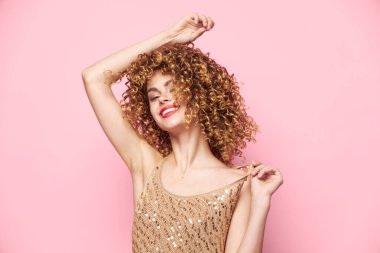 Seksi manken Güler ve ellerini başının üstünde tutar kıvırcık saçlarını 