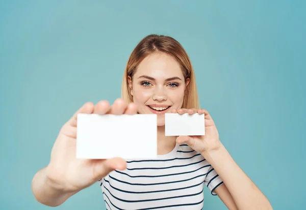 Женщина с визитками разных размеров на синем фоне и полосатой футболкой — стоковое фото