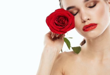Ellerinde kırmızı gül ve makyajlı göz farı olan çıplak omuzlu bir kadın.