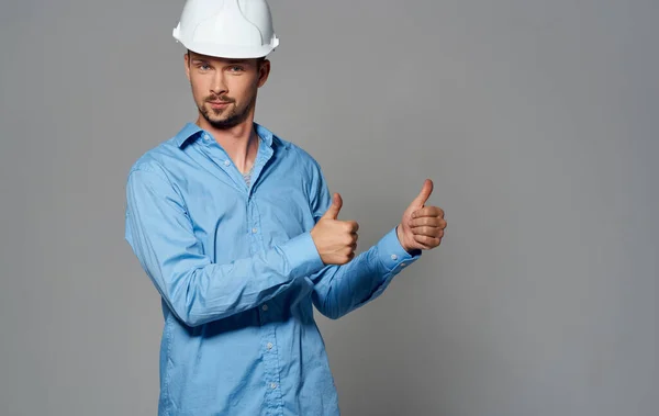 흰색 헬멧을 쓴 건축가와 회색 배경 감정 초상화의 파란색 셔츠를 입은 건축가 — 스톡 사진