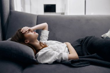 Alnında el ele tutuşan bir kadın kanepeye uzanmış, kendini kötü hissediyordu.