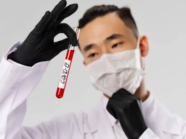 Азіатський чоловік в чорних рукавичках аналіз крові діагностика лабораторні дослідження сірий фон — стокове фото