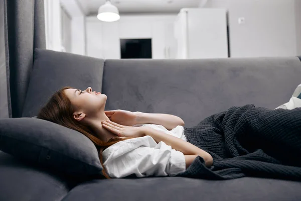 Mulher em casa deitada no sofá coberta com um cobertor de problemas de saúde — Fotografia de Stock