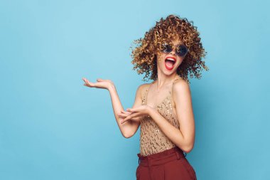 Güzel kadın duyguları kıvırcık saçlar kırmızı dudaklar el hareketleri kahverengi pantolonlar 