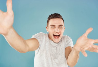 Komik duygusal adam beyaz tişörtlü el hareketleri yakın plan mavi arka plan