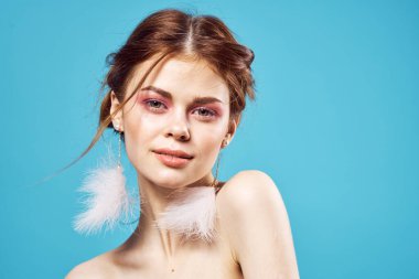 Çekici bir kadın parlak makyaj küpeleri takı omuzları mavi arka plan