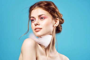 Çekici bir kadın parlak makyaj küpeleri takı omuzları mavi arka plan