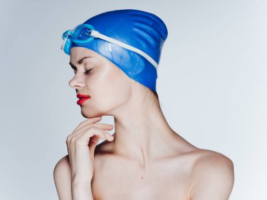 Mavi yüzme şapkası ve açık arkaplanda gözlüklü güzel bir kadının portresi.