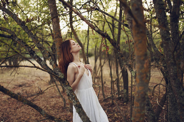 Pretty woman leaning on tree trunk outdoors in garden cropped view. High quality photo