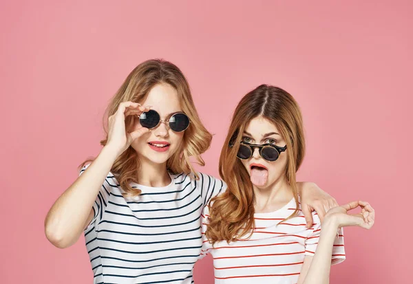 Kobiety w pasiastych koszulkach w okularach przeciwsłonecznych studio mody różowe tło — Zdjęcie stockowe