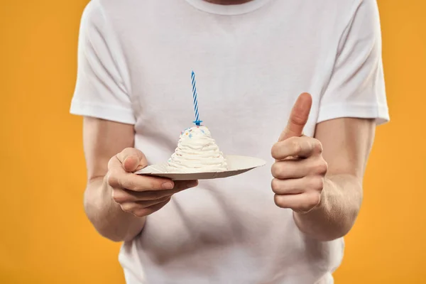 Egy férfi szülinapi tortával a kezében egy sárga háttér születésnapi desszerten. — Stock Fotó