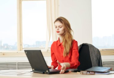 Kırmızı gömlekli kadın sekreter dizüstü bilgisayarlı ofis yöneticisi.