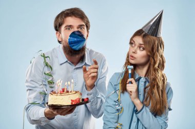 Mavi arka planda parti şapkalı kadın ve mumlu pasta.