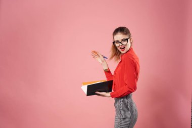 Ofis yöneticisi kılığındaki iş kadını, mali açıdan pembe arka planda çalışıyor.