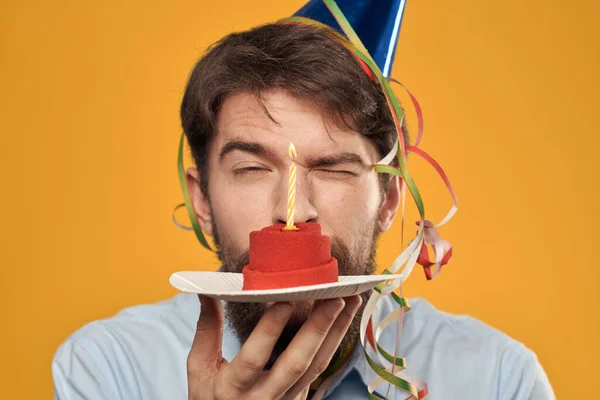 노란 배경 휴일 용초에 케이크를 접시에 담은 남자 — 스톡 사진