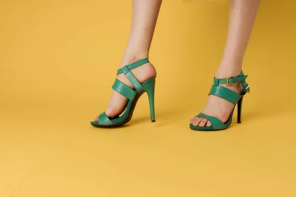 Donna gambe scarpe verdi scarpe alla moda sfondo giallo — Foto Stock