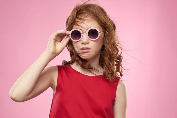곱슬곱슬 한 머리에 둥근 안경을 쓰고 있는 소녀 핑크 색 옷을 즐겨 입는다 — 스톡 사진