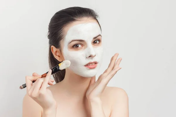 Femme appliquant masque avec pinceau de maquillage pour faire face aux épaules nues — Photo