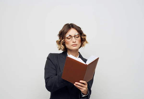 Una donna in giacca e cravatta con un taccuino tra le mani su uno sfondo leggero modello di lavoro — Foto Stock