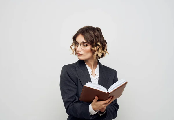 Femme en costume classique avec des lunettes à livre ouvert sur la vue recadrée face — Photo