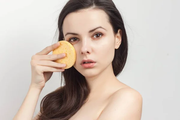 Mujer con hombros desnudos esponjas cerca de cosméticos de la cara cuidado — Foto de Stock