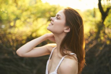 Mutlu kadın ormanda dinleniyor. Güneş ağaçları.