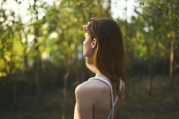 Çekici bir kadın ormanda yeşil ağaçlar yaz günbatımında çimenler — Stok fotoğraf