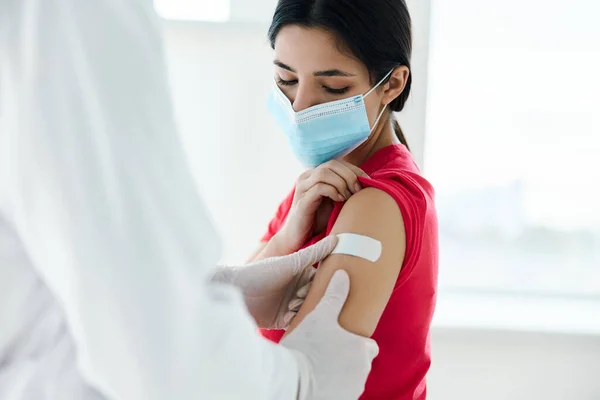 Un médico con una capa blanca pegue la mano del paciente con cinta adhesiva después de la inyección —  Fotos de Stock