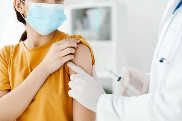 Vista lateral de un médico inyectando una vacuna en el hombro de un paciente que lleva una máscara médica —  Fotos de Stock