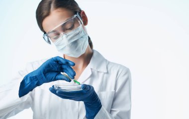 Tıbbi maskeli bir kadın laboratuvar asistanı. Şişede kimyasal bir madde var.