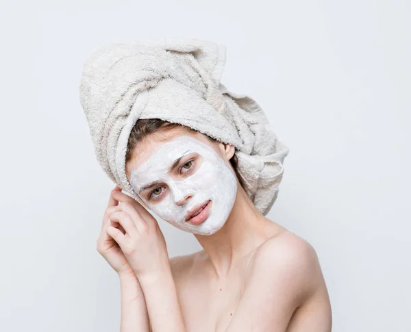 顔のケアに白いマスクを頭の上にタオルを持つ女性 — ストック写真