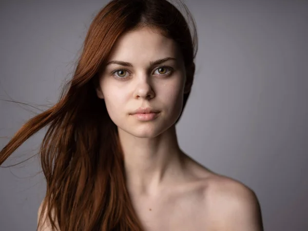 Portrait d'une belle femme aux cheveux roux aux épaules nues sur fond gris gros plan — Photo