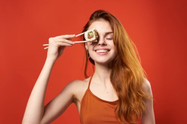 Güzel kadın kızıl saçlı kadın suşi yemek çubukları diyet yemek kırmızı arka plan