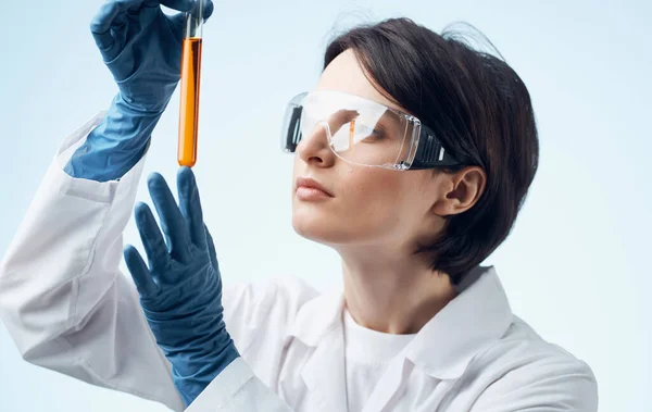 Assistente di laboratorio femminile con una fiaschetta tra le mani occhiali sul viso e un abito medico — Foto Stock