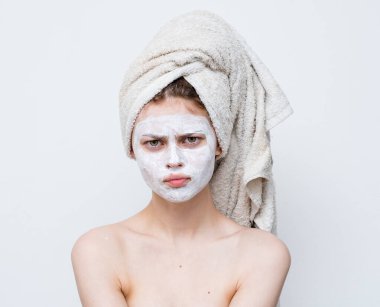 Yüz maskeli, neşeli, temiz ciltli, çıplak omuzlu bir kadın.