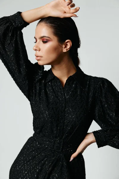 Vacker kvinna med ljus makeup i svart klänning tittar åt sidan poserar — Stockfoto