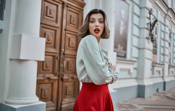 A woman in a red skirt stands near the door of a historic building museum city streets — Stock Photo, Image