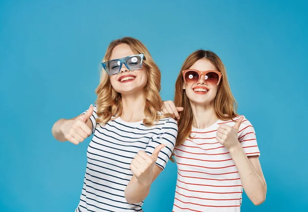 티셔츠를 입고 선글라스를 낀 여성들은 기쁨의 감정 이 파란 배경을 가지고 있습니다. — 스톡 사진