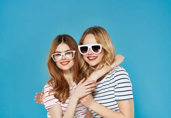 Két vidám barátnő csíkos pólók napszemüveg ölelés barátság életmód vágott kilátás kék háttér — Stock Fotó