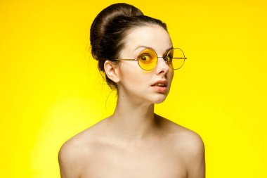 Esmer, çıplak omuzlu. Sarı gözlükler. Duygular izole edilmiş.